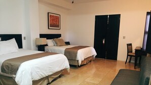 A hotel room with two beds, a sofa, a chair, a desk, and a door. - Hotel Casa las Mercedes (Oaxaca)