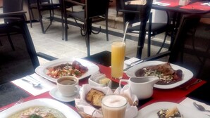 A table set with various dishes including a plate of enchiladas, a glass of orange juice, and a bowl of soup. - Hotel Casa las Mercedes (Oaxaca)