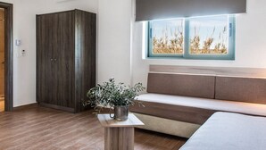 A modern interior with a wooden wardrobe, a cushioned bench, and a window with a view of tall grass. - Gerona Mare (Platanias)