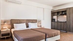 A modern hotel room with two beds, a kitchenette, and a large window. - Gerona Mare (Platanias)