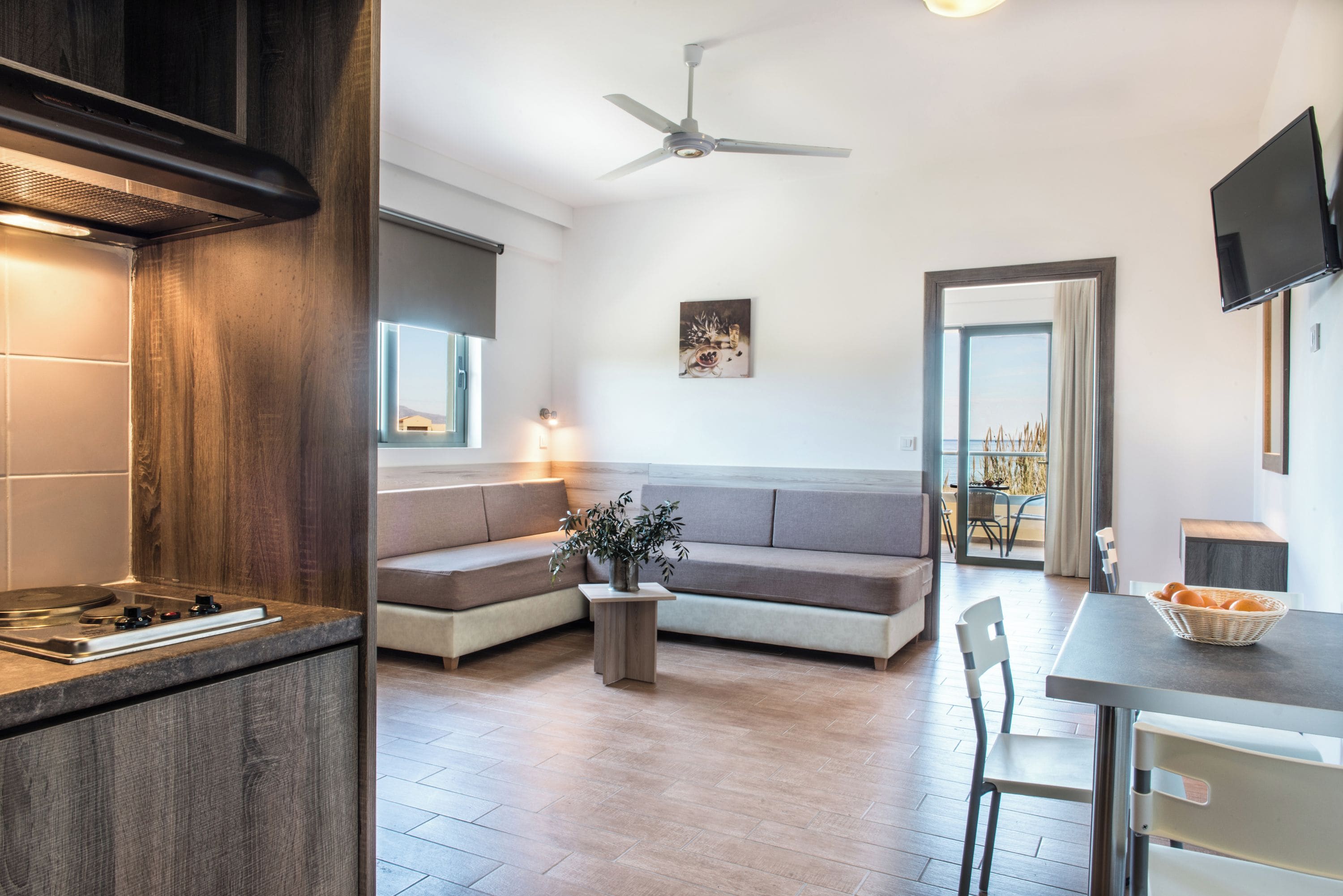 A modern kitchen with a built-in stove, a wooden cabinet, and a ceiling fan.