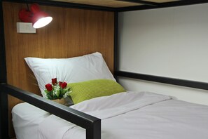 A bed with white bedding, a green pillow, and a red lamp on the wall. - Zleep Inn Chiang Mai - Hostel (Chiang Mai)
