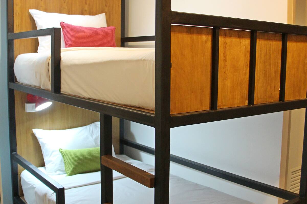 A bunk bed with three levels, each with a mattress and pillows.