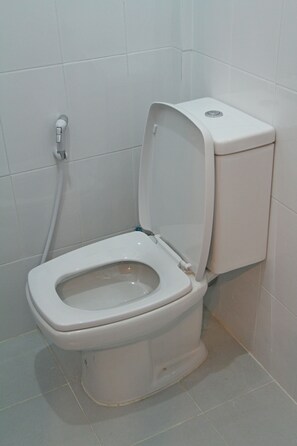 A standard white toilet with a tank and seat, positioned against a tiled wall in a bathroom. - Zleep Inn Chiang Mai - Hostel (Chiang Mai)