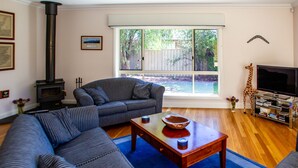 A living room with a sofa, a coffee table, a television, and a fireplace. - Lochnagar Barossa - Adults Only (Tanunda)