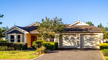 A two-story residential house with a garage, a covered porch, and a well-maintained lawn.