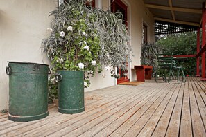 Um deck de madeira com latas de lixo verdes e plantas em vasos.