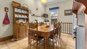 Un coin repas avec une table et des chaises en bois, une cuisine avec des meubles blancs et un luminaire suspendu.
