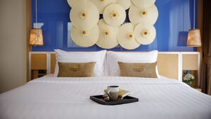 A hotel room with a neatly made bed, a tray with a cup and a book, and a wall decorated with circular patterns. - 9 Suite Luxury Boutique Hotel (Chiang Mai)