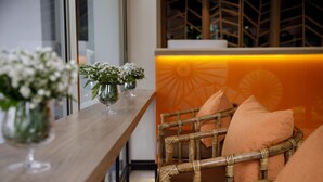 A wooden table with vases of white flowers and a wicker chair with orange cushions. - 9 Suite Luxury Boutique Hotel (Chiang Mai)