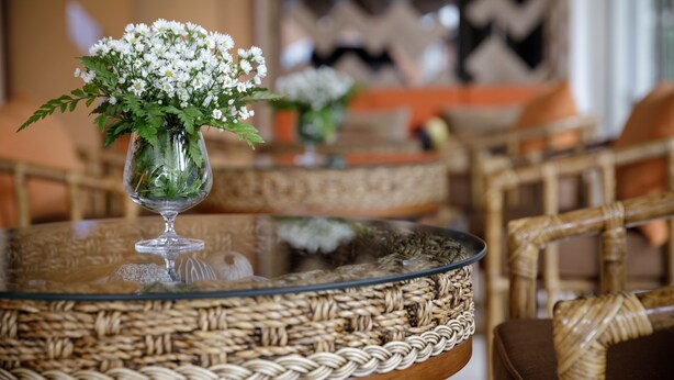 A wicker table with a glass top and a clear vase containing white flowers. - 9 Suite Luxury Boutique Hotel (Chiang Mai)