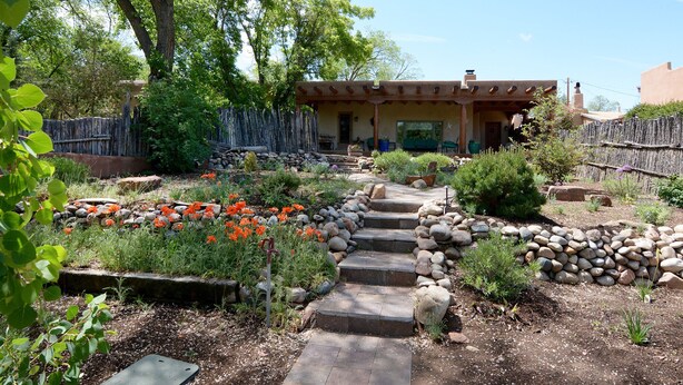 A garden with a stone pathway leading to a house with a covered patio.