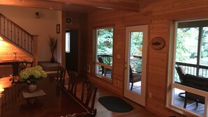 A wooden cabin interior with a dining area, a staircase, and a deck with outdoor seating. - McKenzie Riverfront-w Hottub woodstove+wood (Vida)