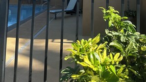 Un immeuble résidentiel à plusieurs étages doté de balcons, d’une piscine et de chaises longues.