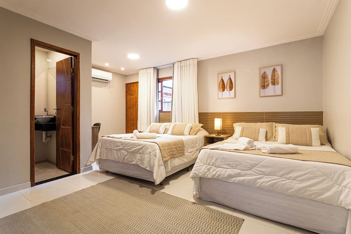 Une chambre d’hôtel avec deux lits, une salle de bain et une fenêtre avec des rideaux.
