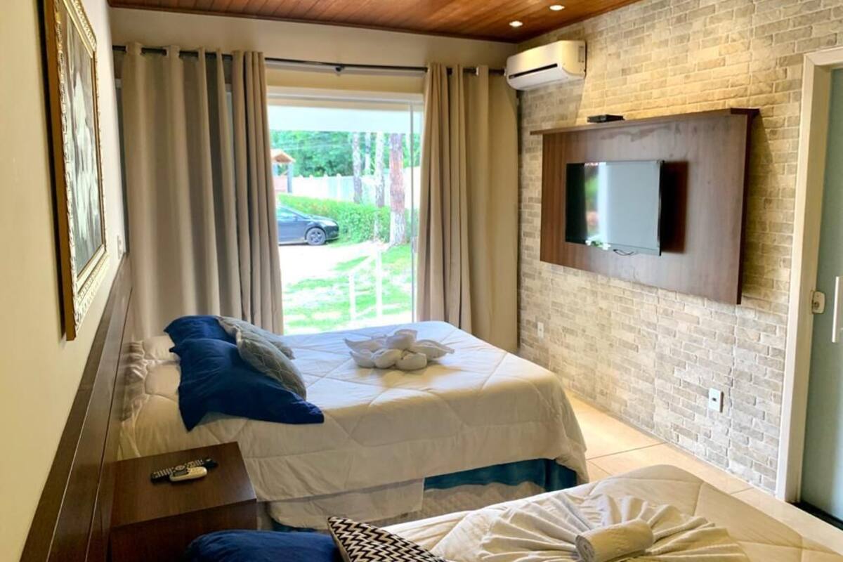Une chambre d’hôtel avec deux lits, un téléviseur fixé au mur et une vue sur l’extérieur.
