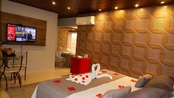 Hotelkamer met een groot bed, een aan de muur bevestigde televisie, een rode koffer en een muur met een geometrisch patroon.
