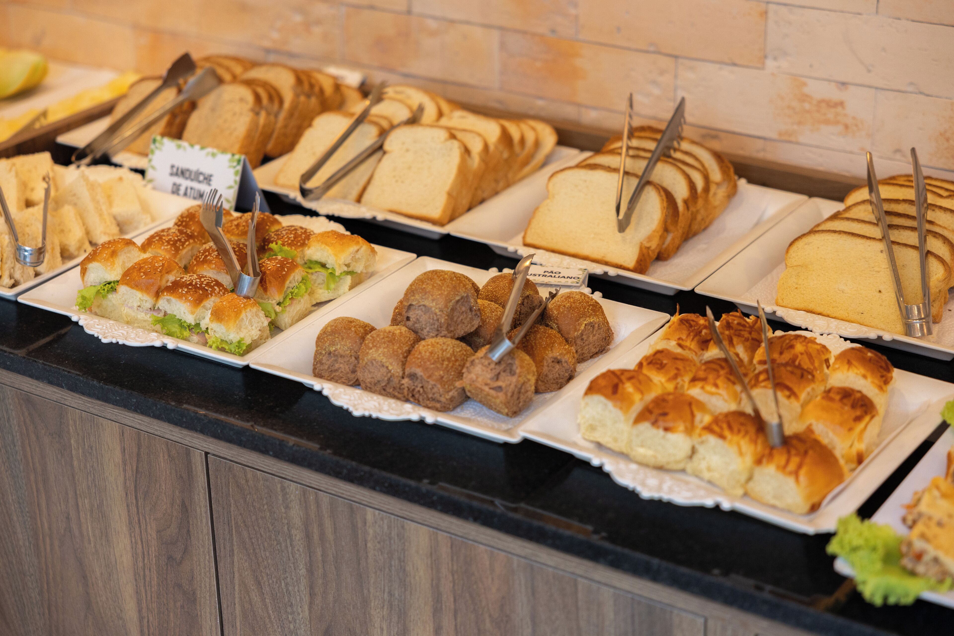 A buffet with various food items including sandwiches, croquettes, and rolls.