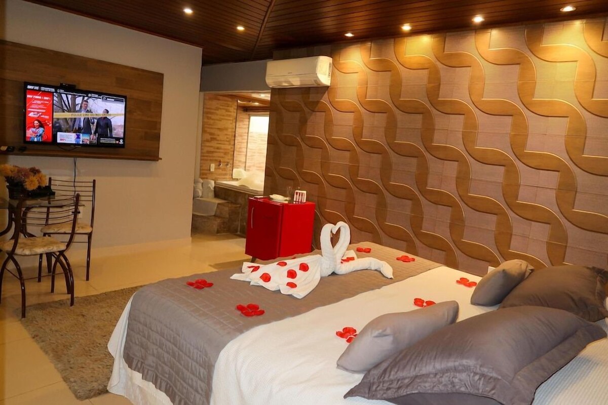 Una habitación de hotel con cama, televisión, una caja roja y una pared con diseño geométrico.