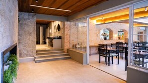 A modern interior with a stone wall, wooden ceiling, and a dining area with tables and chairs. - Pousada Recanto de Moriá (Itatiaia)