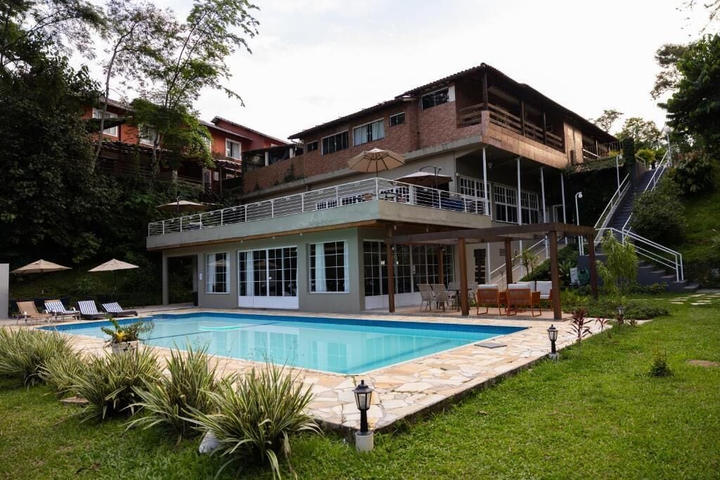 A two-story building with a swimming pool, outdoor seating, and a staircase leading to an upper level.