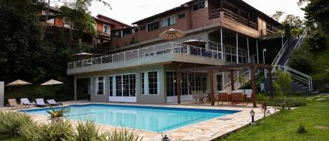 A two-story building with a swimming pool, outdoor seating, and a staircase leading to an upper level.