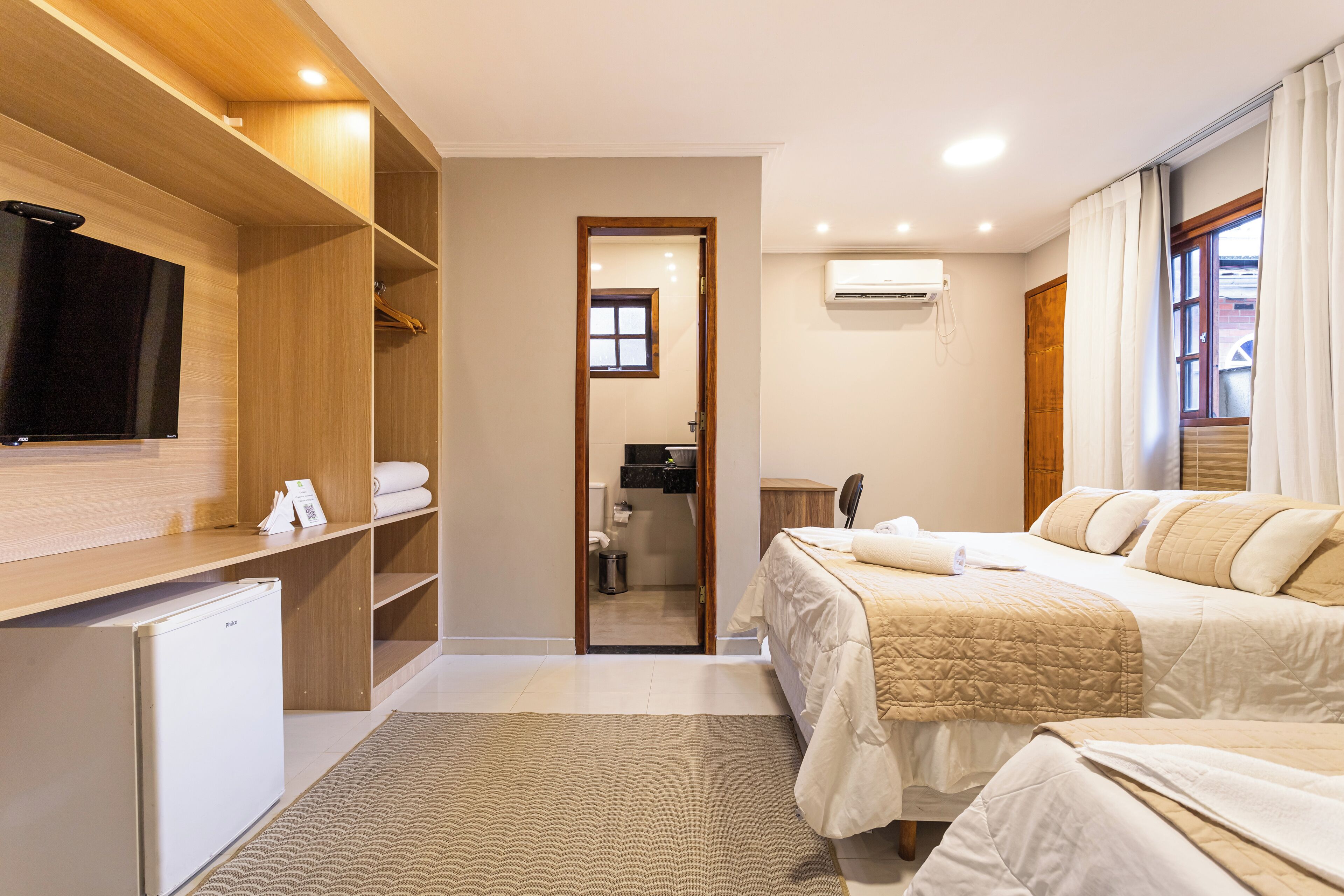 Une chambre d’hôtel équipée d’un lit, d’une télévision, d’une armoire et d’un petit réfrigérateur.