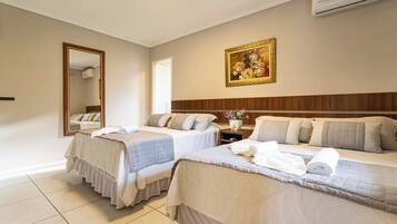 A hotel room with two beds, a large mirror, a painting, and an air conditioning unit.