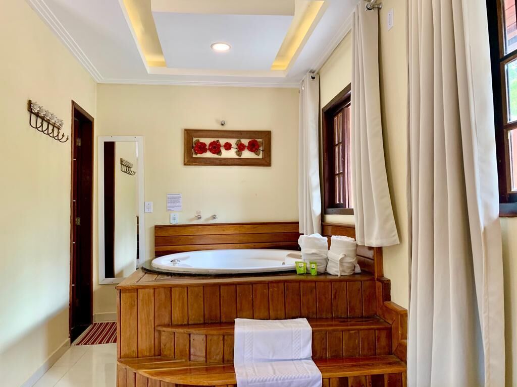 Un baño con una banca de madera, una bañera y un perchero para toallas.