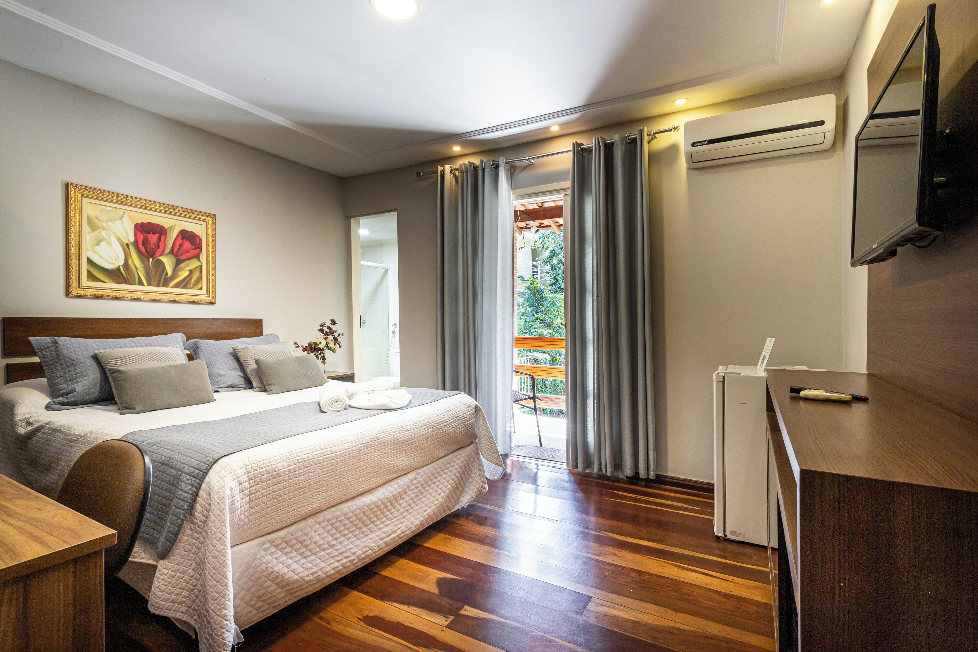 Habitació d'hotel amb llit, escriptori, aire condicionat, televisió i un quadre a la paret.