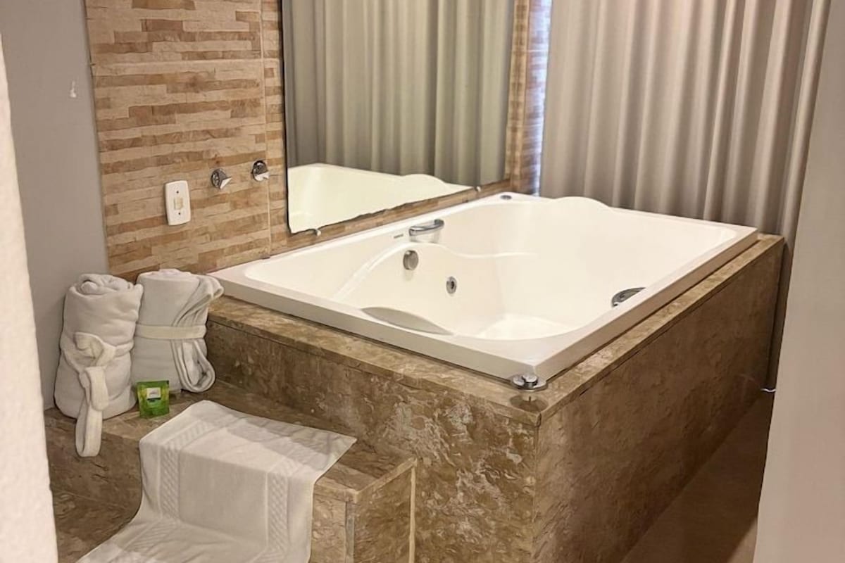 Un baño con una bañera grande, un espejo y un perchero para toallas.