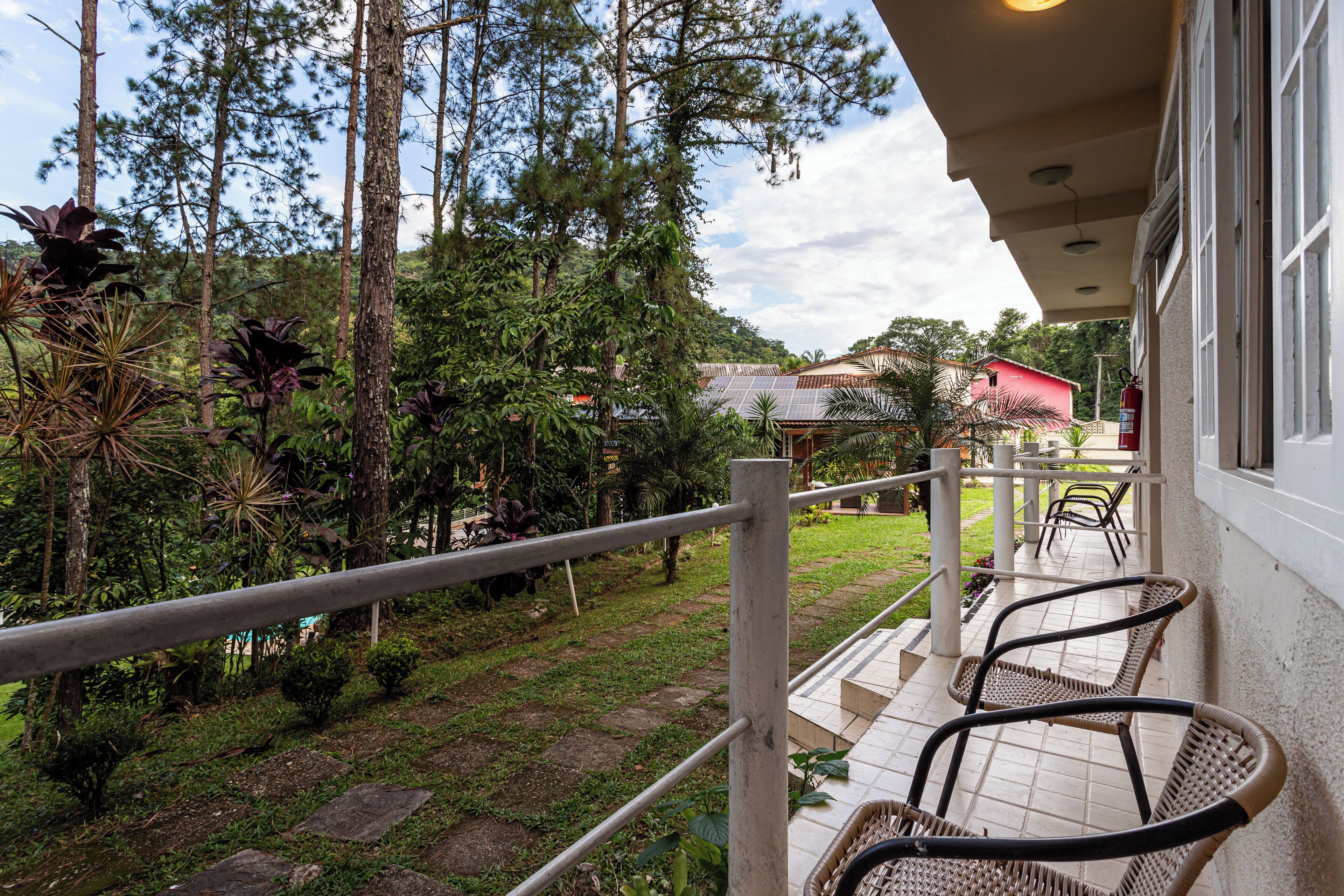 Un balcon avec des chaises, une balustrade et une vue sur un jardin et des arbres.