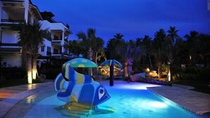 Une piscine agrémentée d’une fontaine en forme de dauphin, avec des palmiers en arrière-plan.