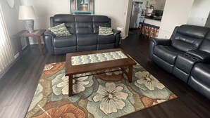 A living room with a sofa, a coffee table, and a patterned rug. - Holiday home winter / summer (Winter Garden)