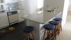 A modern kitchen with white cabinetry, a dishwasher, and a bar area with stools. - Holiday home winter / summer (Winter Garden)