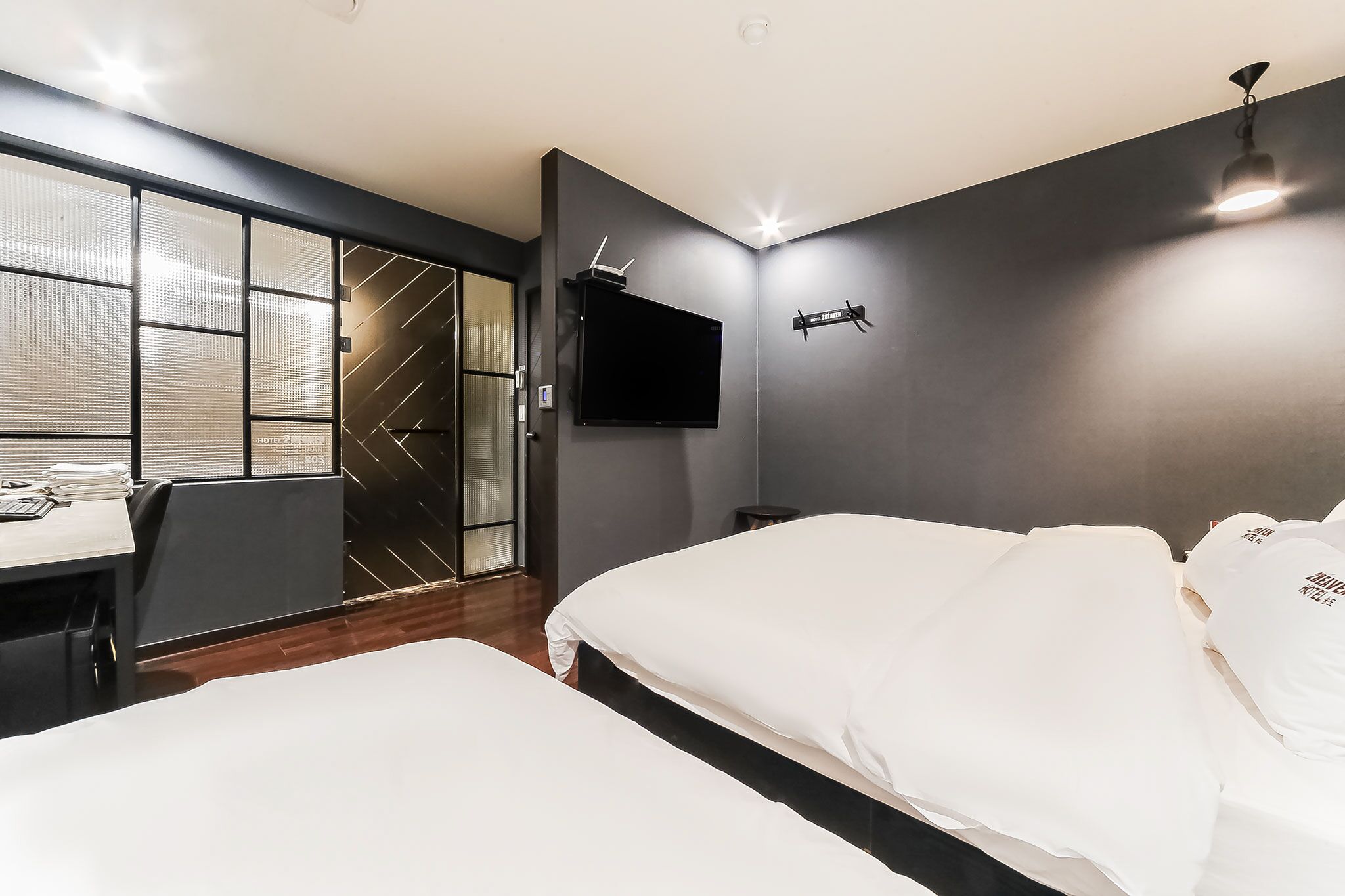 A modern hotel room with a large bed, a desk, and a TV mounted on the wall.