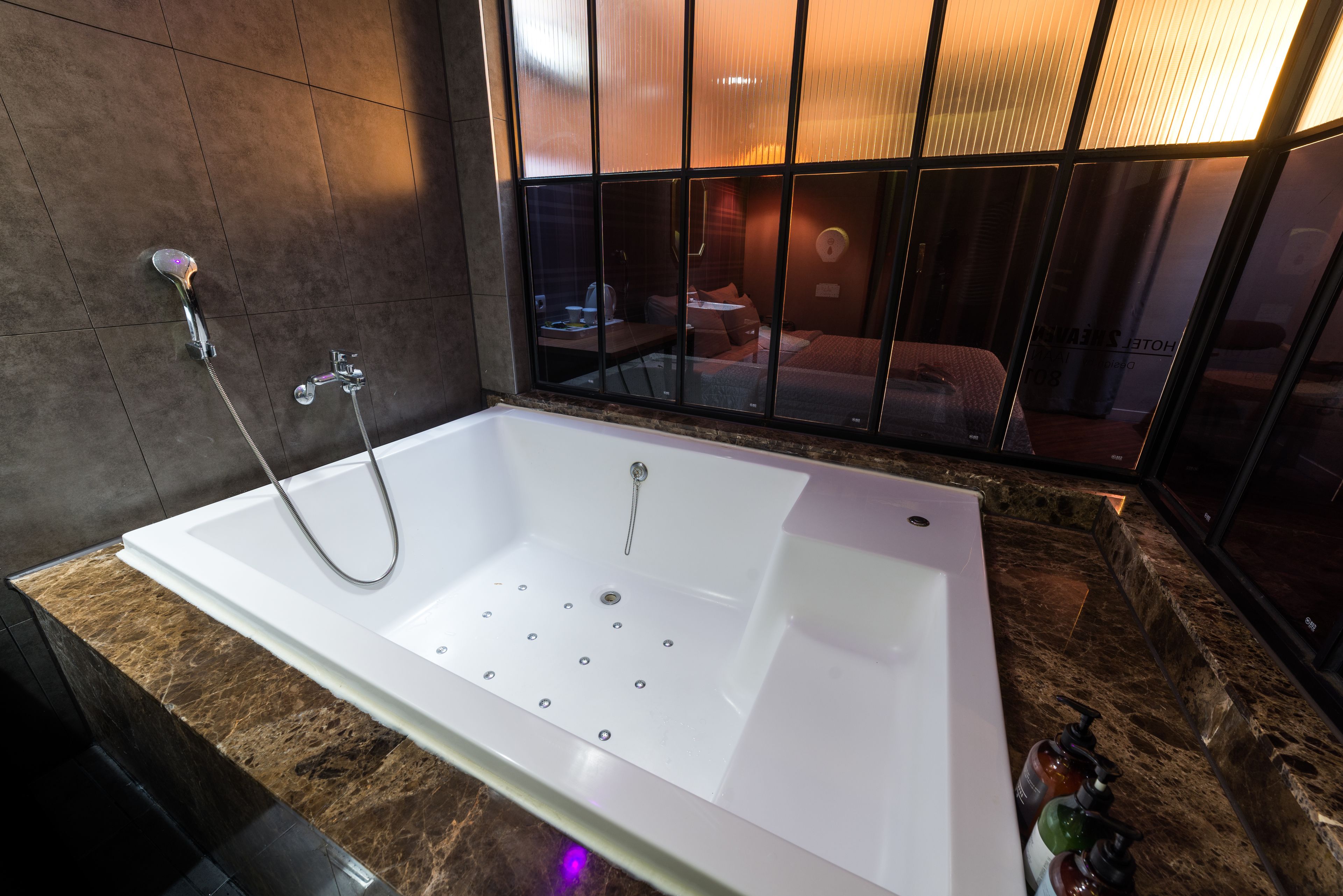 A modern bathroom with a large bathtub, a shower, and a glass partition.