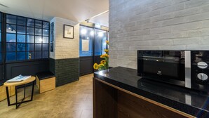 Una cocina moderna con cubierta negra, microondas y pared de ladrillo.
