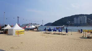 Une plage avec des tentes, des parasols et une étendue d’eau.