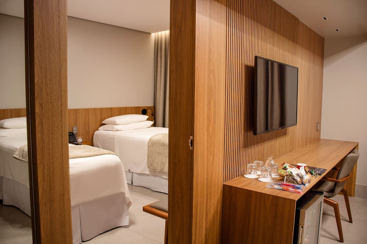 Une chambre d’hôtel avec deux lits, un bureau en bois, un téléviseur à écran plat et un mini-bar.