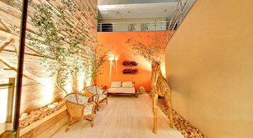 Una habitación acogedora con una cama, dos sillas, una mesita y una pared con una estructura similar a un árbol.