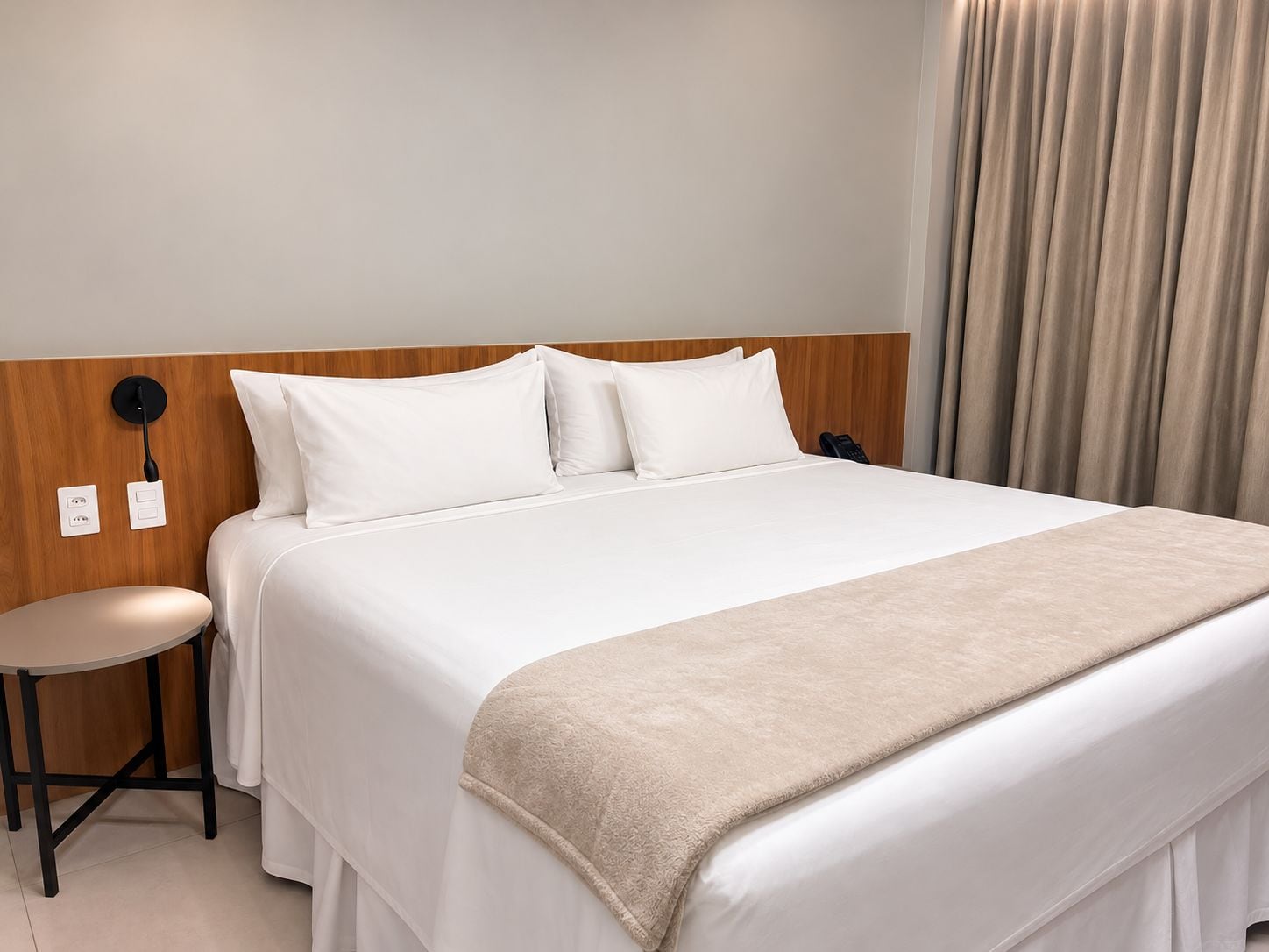 Una habitación de hotel con una cama, una mesita de noche, una lámpara y un teléfono.