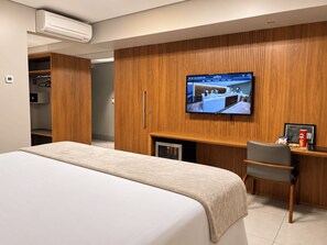 A hotel room with a bed, a desk, a television, and a minibar. - Hotel Taiamã (Cuiabá)