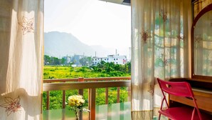 A balcony with a view of a green landscape and buildings in the distance. - Sabina Guesthouse (Kamala)