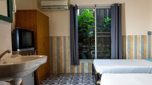 A small, compact room with a single bed, a sink, and a television. - Sabina Guesthouse (Kamala)