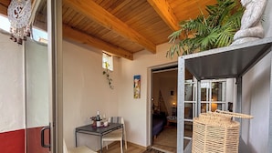 Une pièce chaleureuse avec un plafond en bois, une table à manger avec des chaises, une petite plante et un panier en osier posé sur une étagère.
