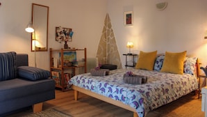 Ein Schlafzimmer mit einem Bett, einer Couch, einem Beistelltisch, einer Lampe und einem Bücherregal.