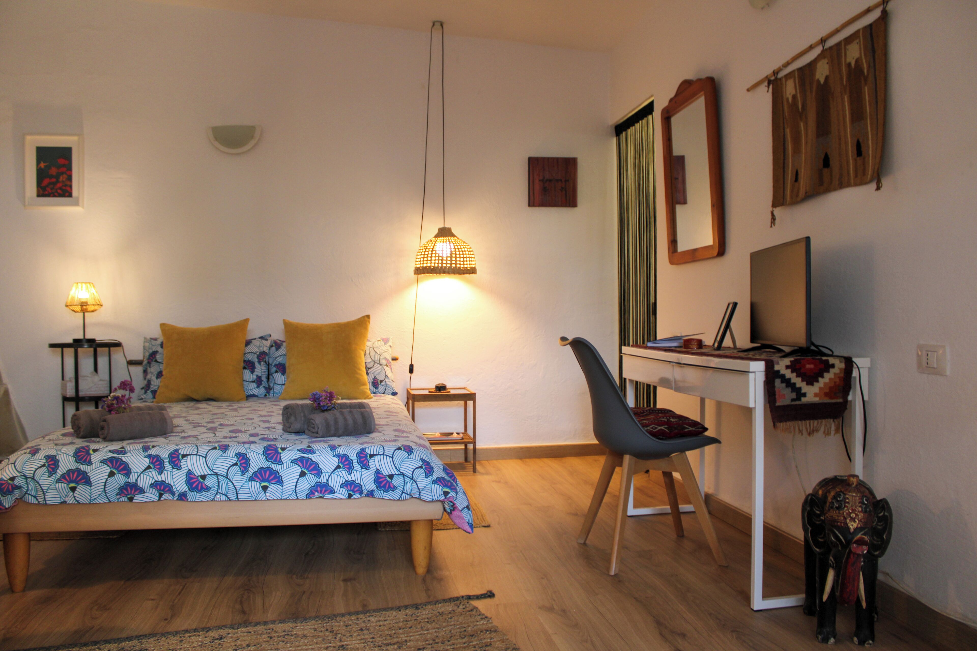 A bedroom with a bed, bedside tables, a desk, a chair, and a small elephant decoration.