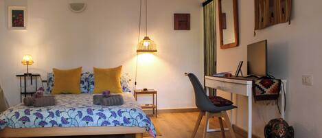 A bedroom with a bed, bedside tables, a desk, a chair, and a small elephant decoration.