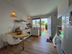 Una cocina moderna con gabinetes blancos, una mesa de comedor de madera y dos lámparas colgantes.